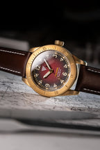 Orologio Vertigo Tritone bronzo con quadrante rosso alga appoggiato su mappa, vista angolata