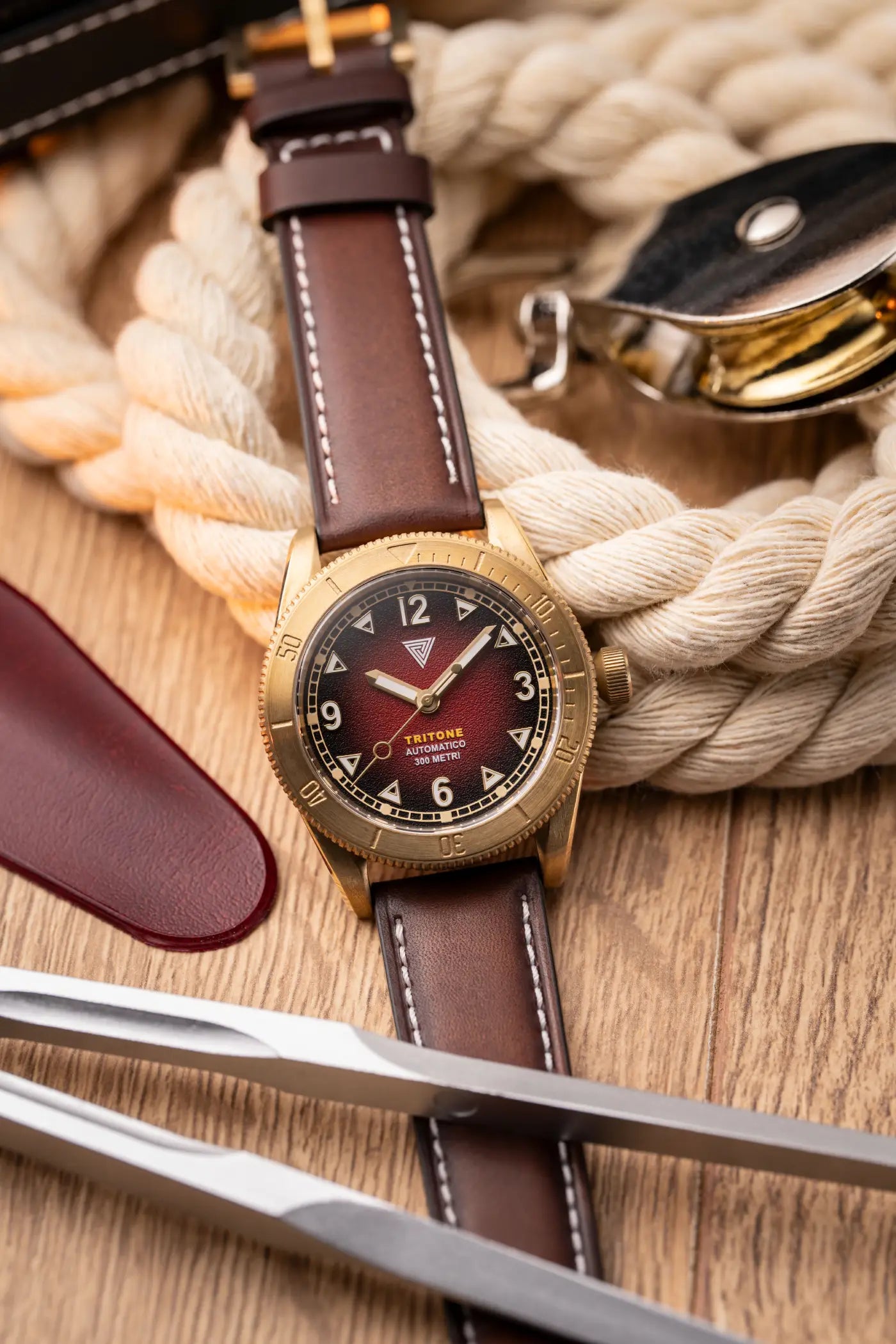 Orologio Vertigo Tritone bronzo con quadrante rosso alga su corda nautica e accessori, vista lifestyle