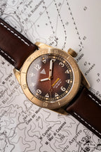 Orologio Vertigo Tritone bronzo con quadrante roccia rossa su mappa, vista angolata