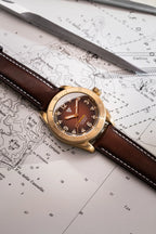 Orologio Vertigo Tritone bronzo con quadrante roccia rossa su mappa con strumenti, vista lifestyle