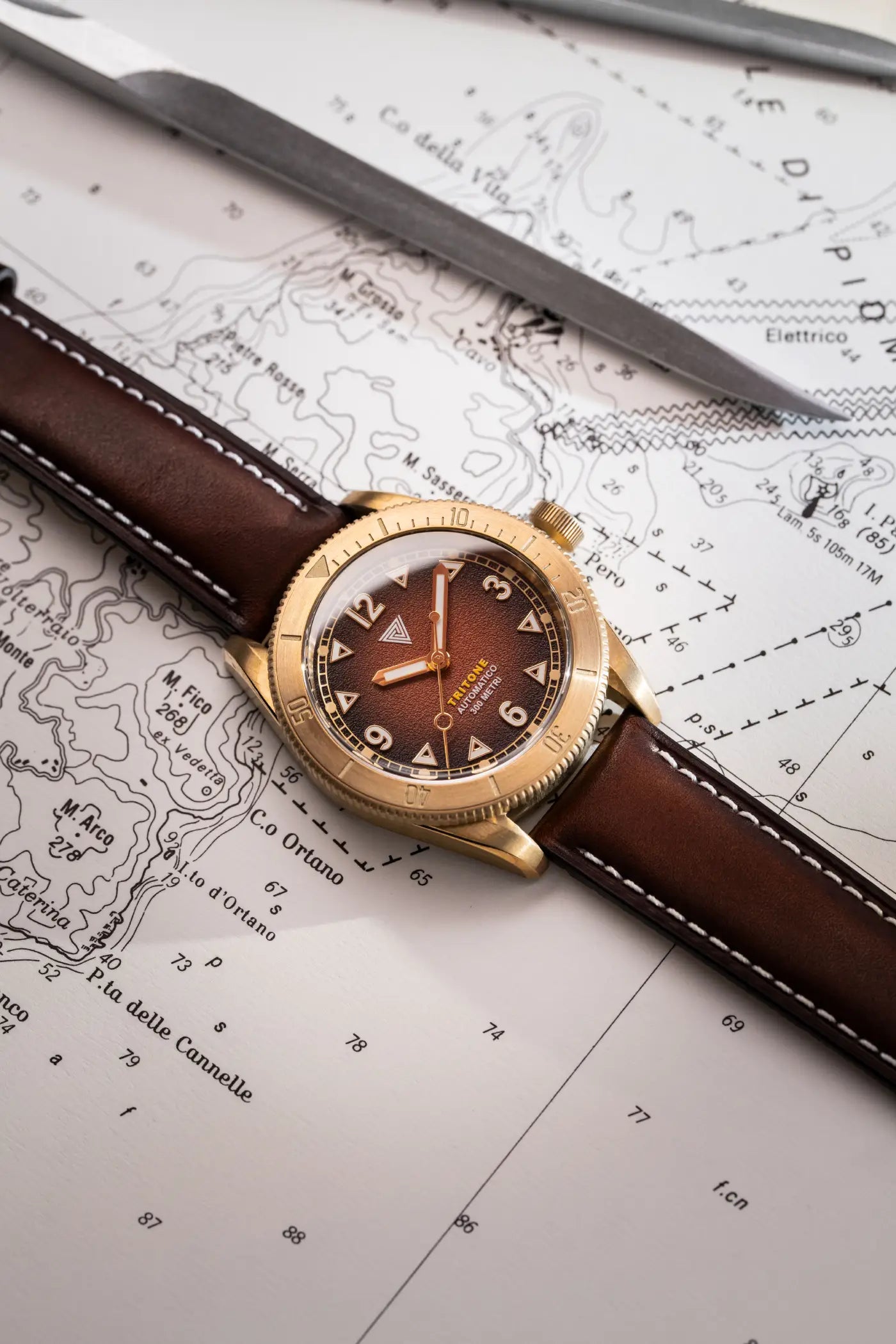 Orologio Vertigo Tritone bronzo con quadrante roccia rossa su mappa con strumenti, vista lifestyle