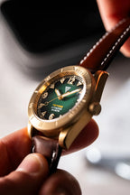 Orologio Vertigo Tritone bronzo tenuto in mano con cinturino in pelle marrone