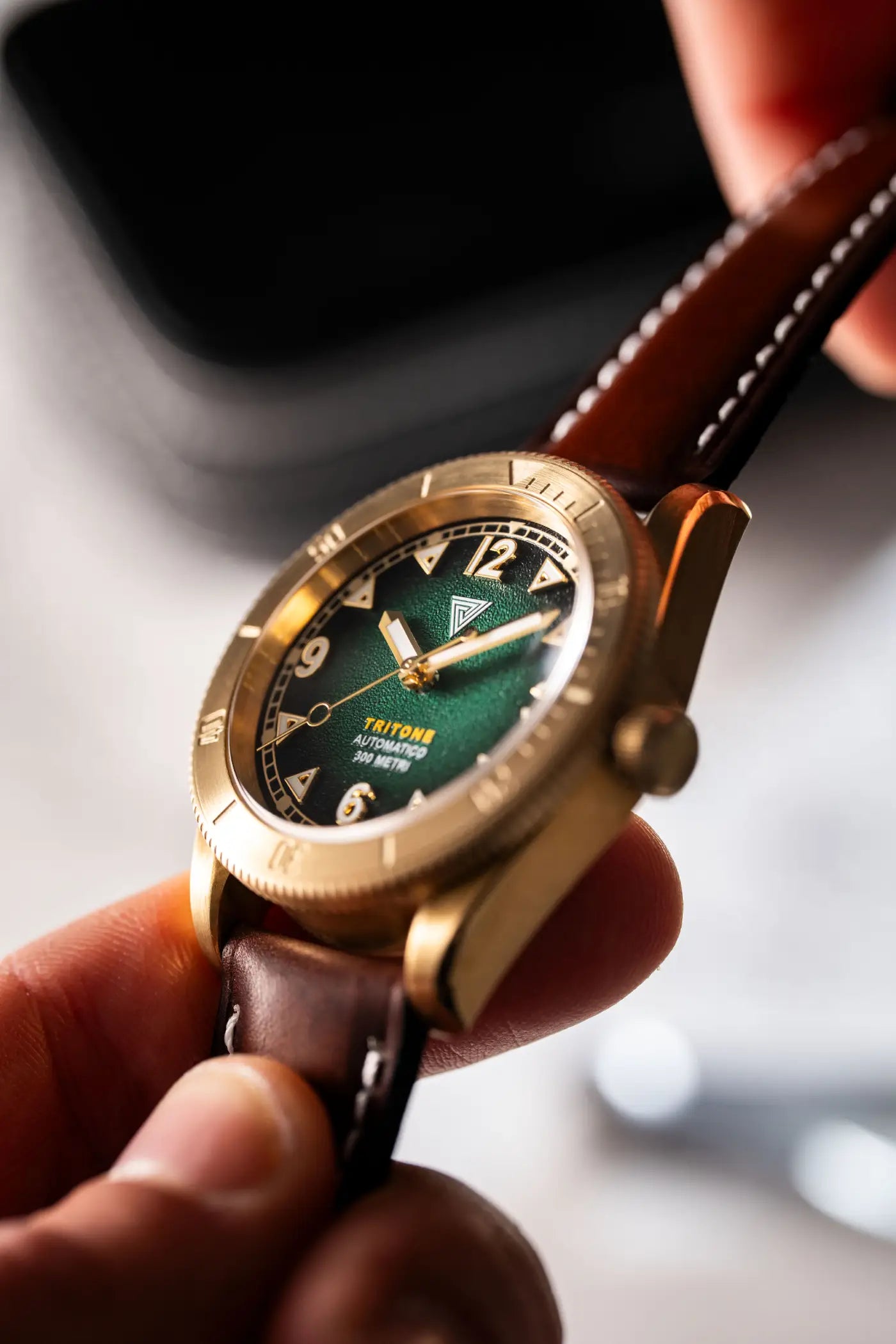 Orologio Vertigo Tritone bronzo tenuto in mano con cinturino in pelle marrone